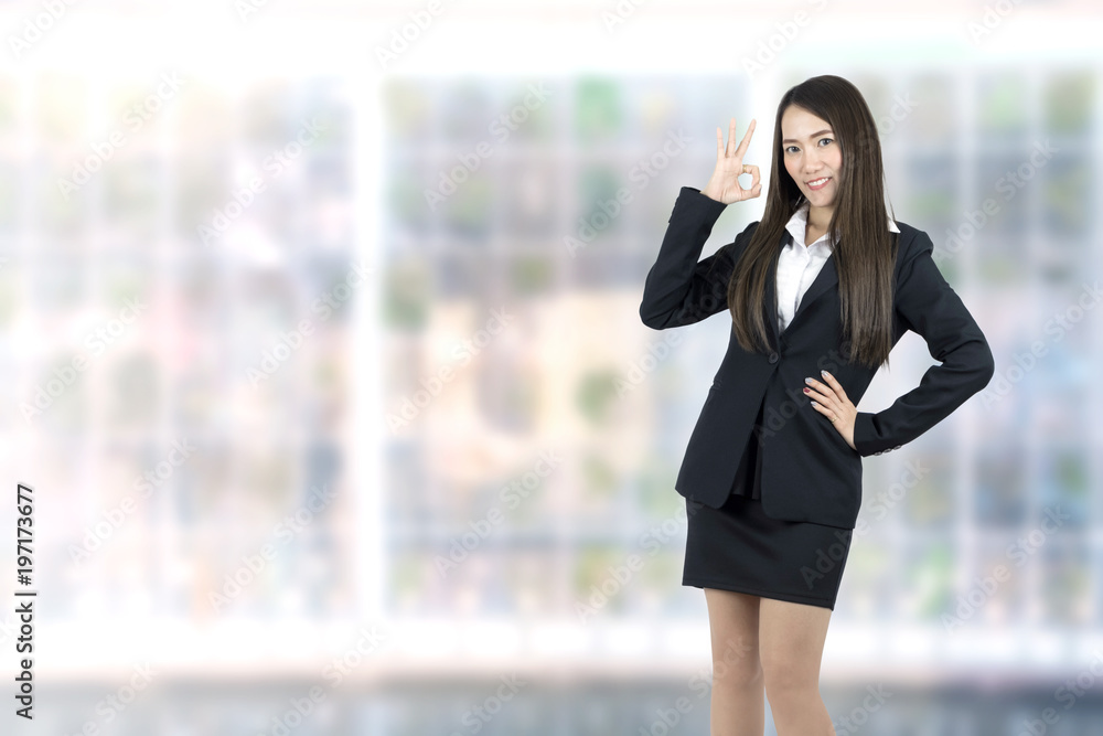 Fototapeta premium Asian young Businesswoman showing OK hand sign smiling happy in office background.