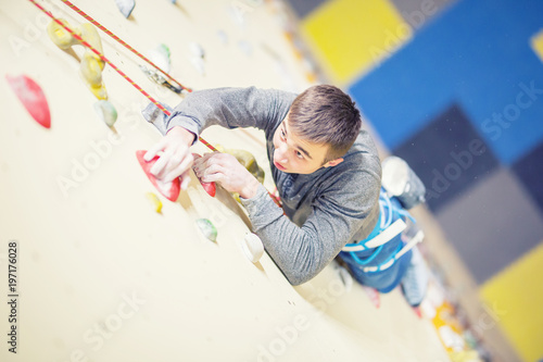 Climber on wall.Young man practicing rock climbing on a rock wall indoors