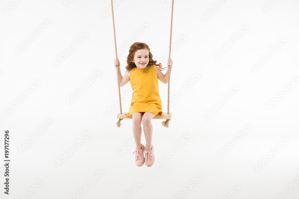 Little stylish child in dress riding on swing isolated on white