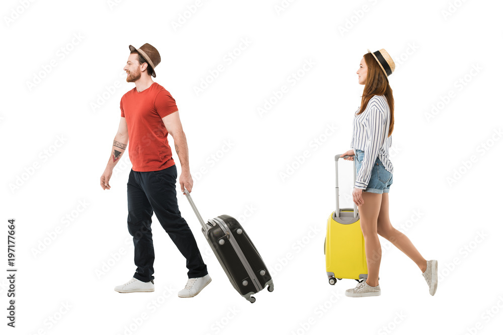 Stylish couple of tourists in hats carrying suitcases isolated on white, travel concept Stylish couple of tourists in hats carrying suitcases isolated on white, travel concept