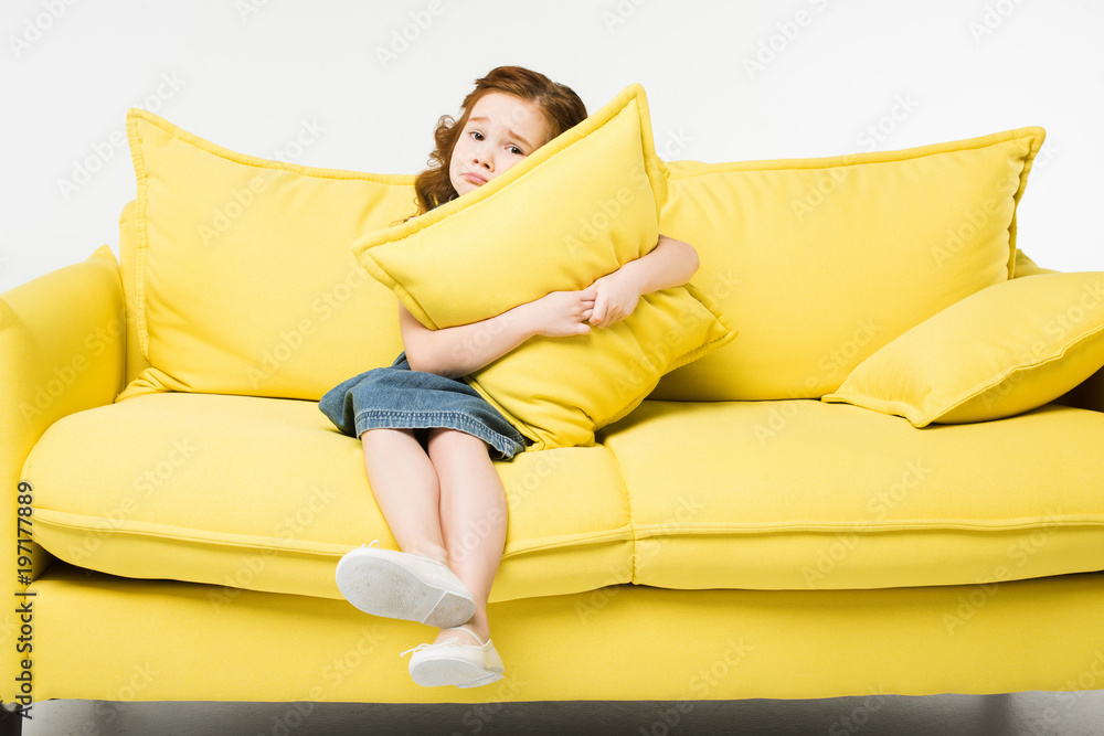 Little cute child embracing cushion while sitting on sofa isolated on white Little cute child embracing cushion while sitting on sofa isolated on white