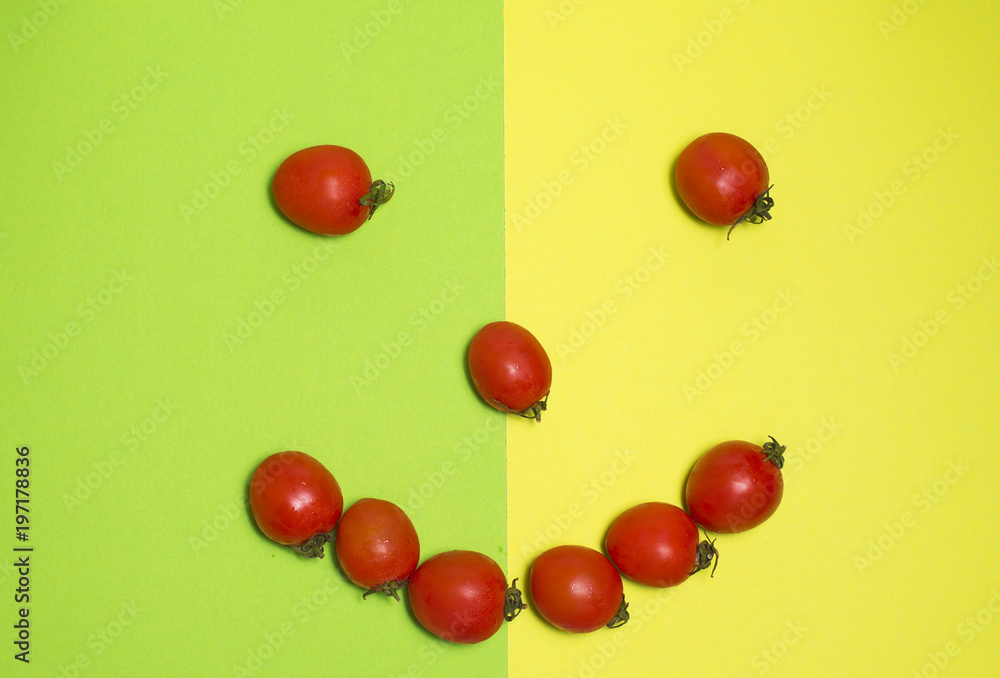 fresh red cherry tomatoes arranged in the shape of a smiling face on a green and yellow background fresh red cherry tomatoes arranged in the shape of a smiling face on a green and yellow background