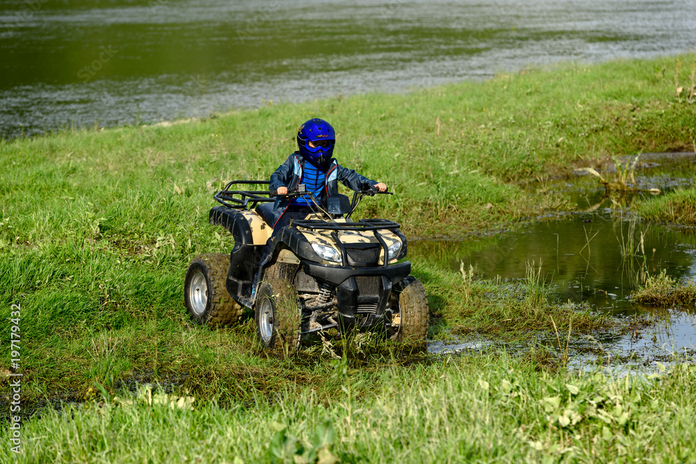 The boy is traveling on an ATV.