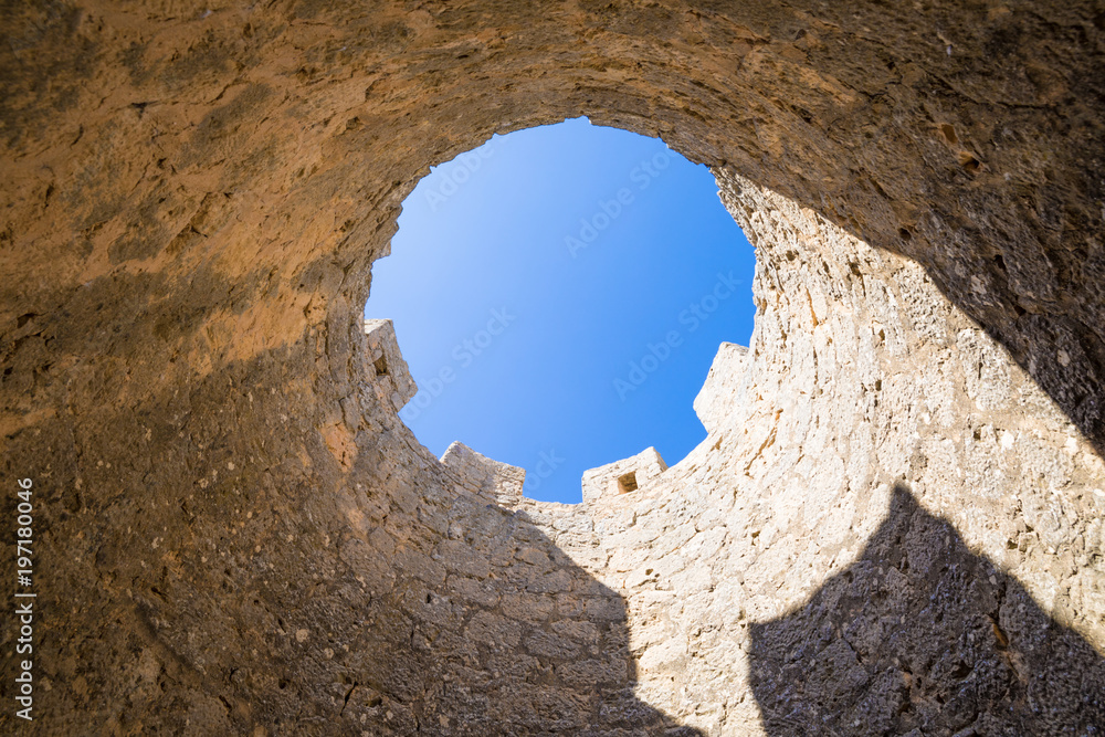 battlements of castle tower seen from below, as a circle with blue sky, in Penaranda de Duero village, landmark and public monument from eleventh century, in Burgos, Castile and Leon, Spain, Europe
