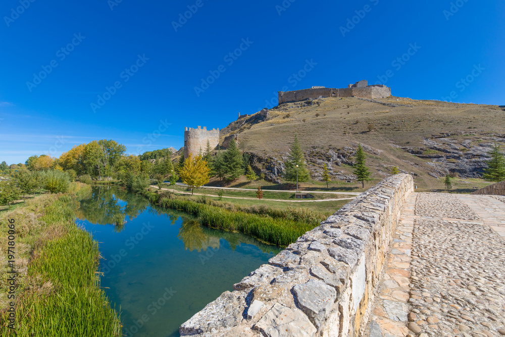 scenary with roman bridge and ruins of castle, landmark and public monument from tenth century, in Burgo de Osma, Soria, Spain, Europe, reflected on water of Ucero river
