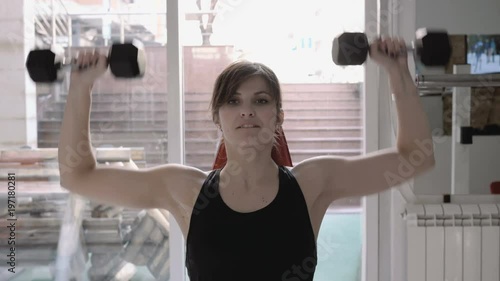 Seated shoulder press, woman in gym