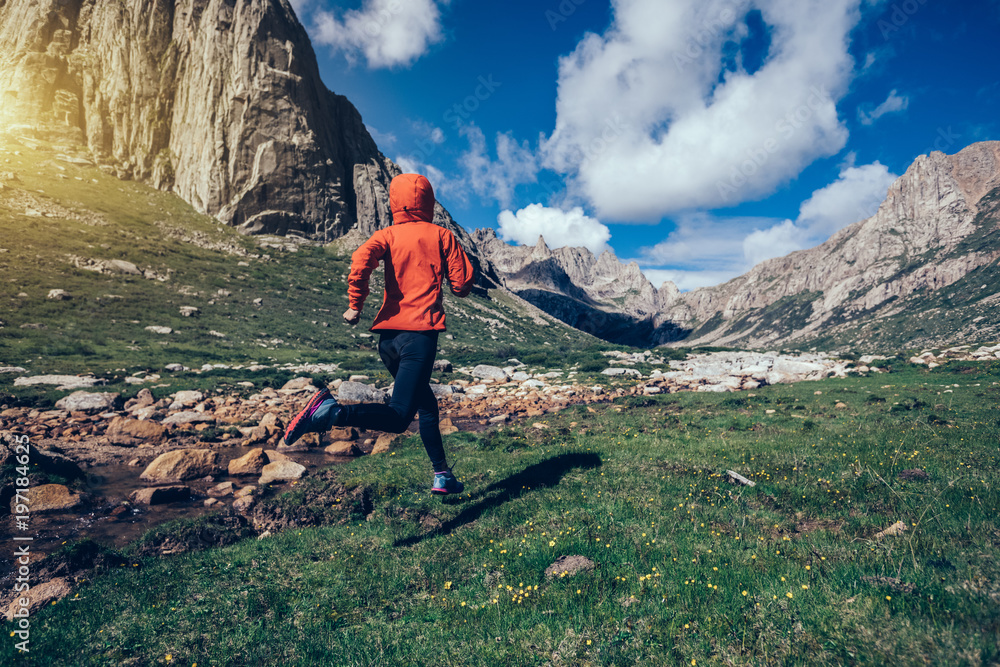 Naklejka premium woman trail runner running on beautiful mountains