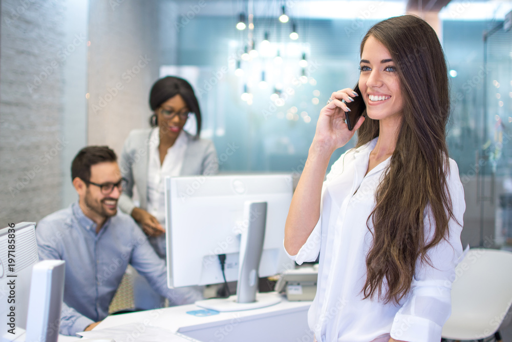 Smiling young business woman talking on mobile phone in office Smiling young business woman talking on mobile phone in office