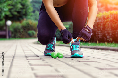 Sports concepts - woman tying shoe laces. Closeup of female legs sport fitness runner ready for jogging outdoors on alley
