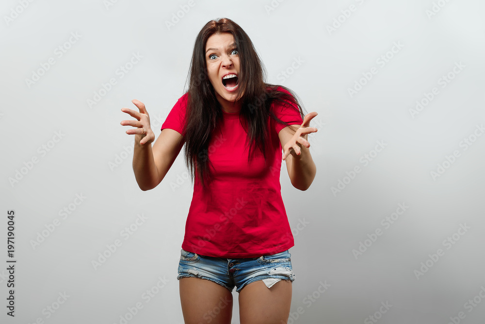 A young, beautiful girl is not happy with something, she screams. Isolated on a light background. Different human emotions, feelings of facial expression, attitude, perception A young, beautiful girl is not happy with something, she screams. Isolated on a light background. Different human emotions, feelings of facial expression, attitude, perception