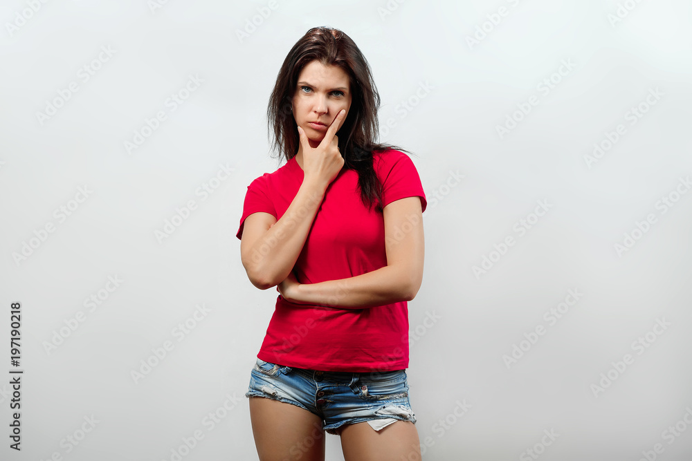 A young, beautiful girl looks inquiringly. Isolated on a light background. Different human emotions, feelings of facial expression, attitude, perception, body language, reaction. A young, beautiful girl looks inquiringly. Isolated on a light background. Different human emotions, feelings of facial expression, attitude, perception, body language, reaction.