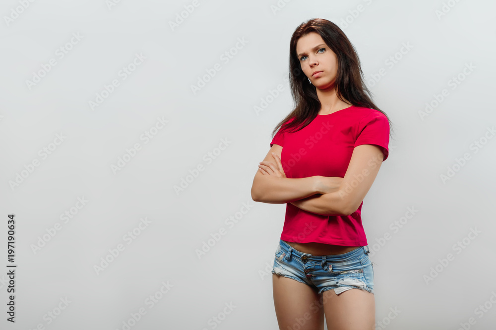A young, beautiful girl crossed her arms. Isolated on a light background. Different human emotions, feelings of facial expression, attitude, perception, body language, reaction. A young, beautiful girl crossed her arms. Isolated on a light background. Different human emotions, feelings of facial expression, attitude, perception, body language, reaction.