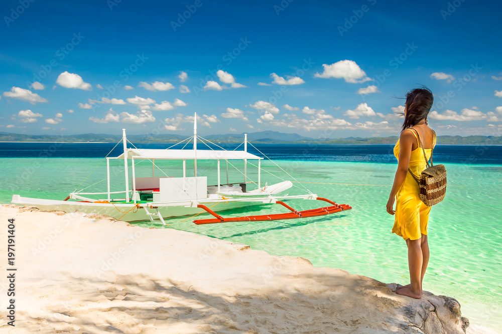 Young woman with yellow dress standing in the shade ona beach an Young woman with yellow dress standing in the shade ona beach an
