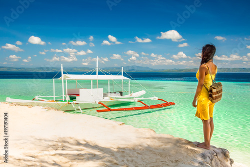 Young woman with yellow dress standing in the shade ona beach an photo
