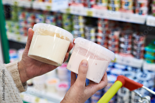 Buyer hands with plastic yogurt jars at grocery