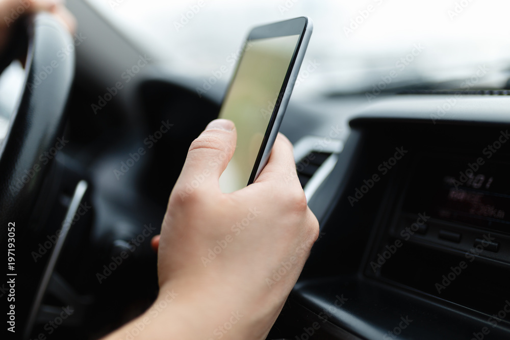 Modern smartphone with blank screen with copy space for your text or design, close-up of male driver hands using mobile phone in luxury car. Phone's touch screen and GPS navigation.