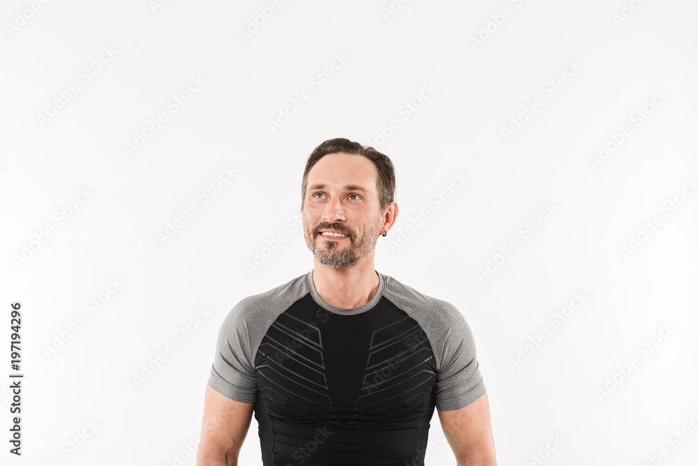 Portrait of masculine man 30s wearing sportswear looking upward on copyspace with smile and satisfied look after doing sports, isolated over white background Portrait of masculine man 30s wearing sportswear looking upward on copyspace with smile and satisfied look after doing sports, isolated over white background