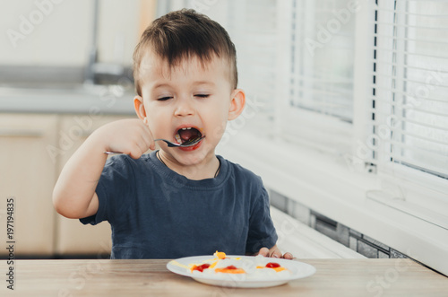 a child in the kitchen eats eggs or omelets in the afternoon