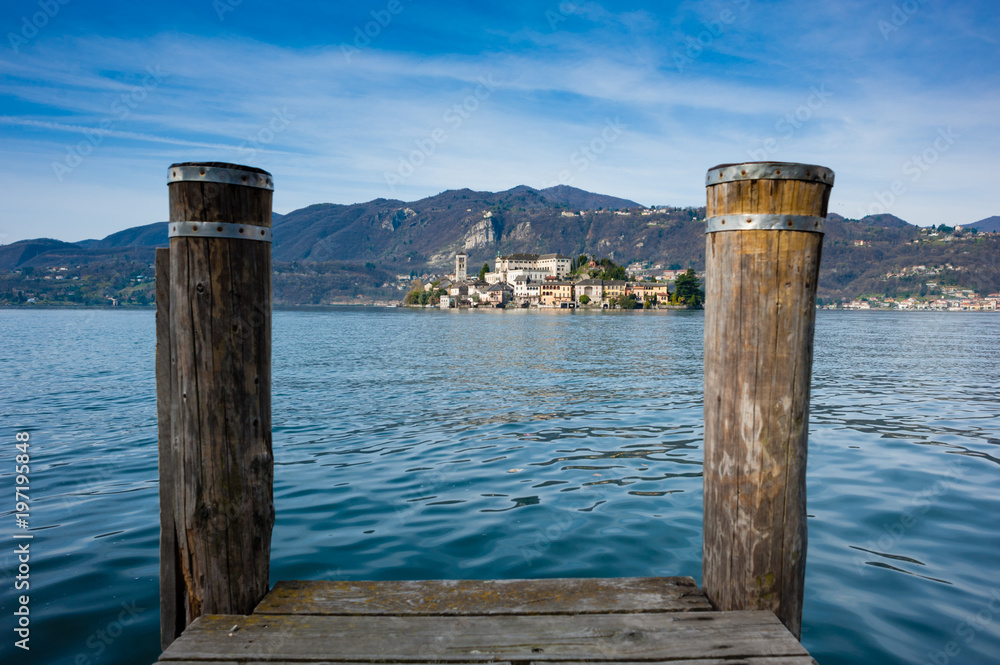 Wooden dock on Lake Orta, opposite the island of San Giulio island with a Benedictine nunnery monastery Wooden dock on Lake Orta, opposite the island of San Giulio island with a Benedictine nunnery monastery
