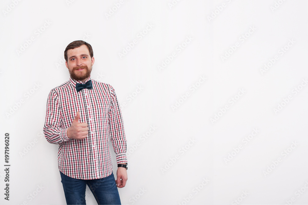 Fototapeta premium Young caucasian bearded man showing thumb up sign. In studio with white background and copyspace