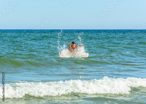 A sports man jumping over the sea waves in the black sea photo