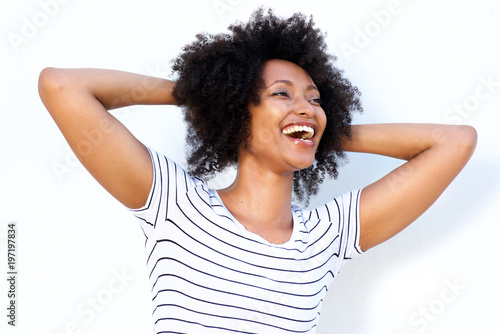 Close up laughing young african woman with hands in hair © mimagephotos