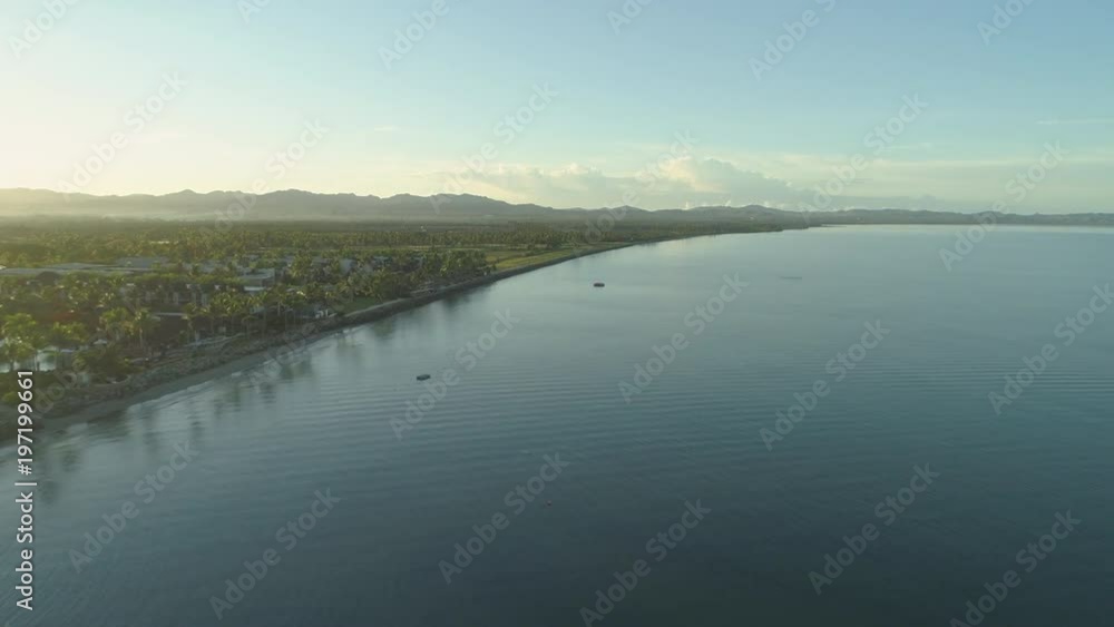 AERIAL: Tropical sunrise illuminates high end hotel complex and perfect green golf course with a stunning view of the calm sea. Fancy accommodation resort on tropical island is empty during off season AERIAL: Tropical sunrise illuminates high end hotel complex and perfect green golf course with a stunning view of the calm sea. Fancy accommodation resort on tropical island is empty during off season