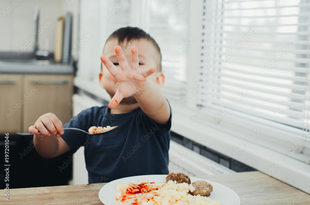 little baby boy in the kitchen eating pasta with cutlets, very tasty little baby boy in the kitchen eating pasta with cutlets, very tasty