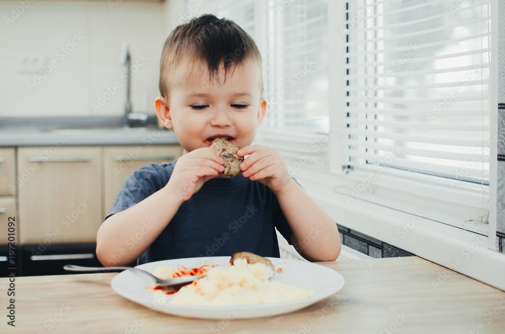 little baby boy in the kitchen eating pasta with cutlets, very tasty little baby boy in the kitchen eating pasta with cutlets, very tasty