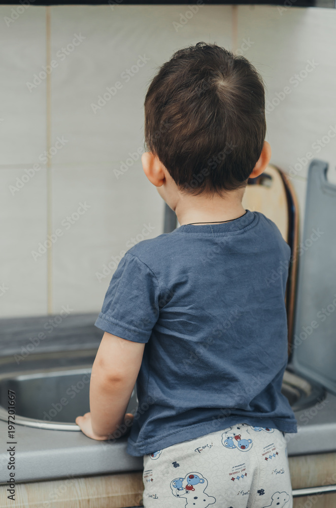 The little boy washes his hands under the crane on his own The little boy washes his hands under the crane on his own