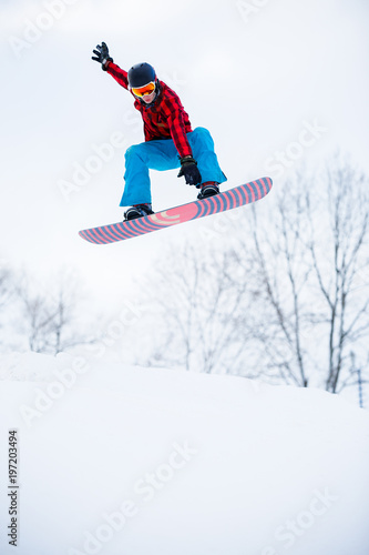 Picture of sports man with snowboard jumping in snowy resort