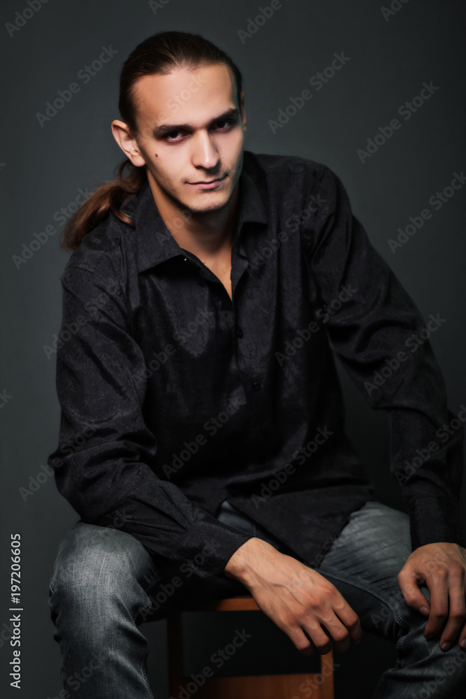 Handsome guy and the photographer is holding a professional camera in a black shirt. Studio photo on a gray background. Handsome guy and the photographer is holding a professional camera in a black shirt. Studio photo on a gray background.