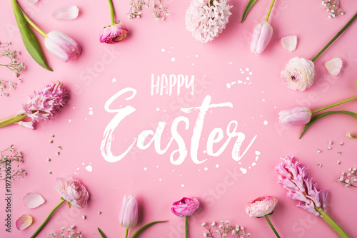 Photography Happy Easter phrase and spring flat lay on a pink bacground.