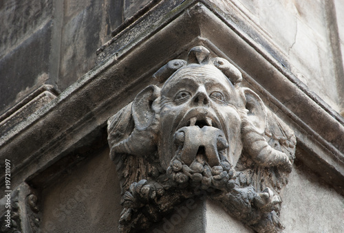 Gargoyle with protruding tongue. Architectural detail of old house in medieval town of Arles. Provence, France.