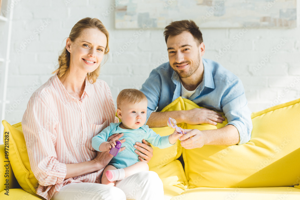 Obraz premium Mother holding infant daughter while father giving her toy