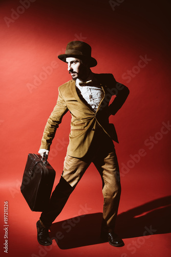 man posing in studio with suitcase in hands