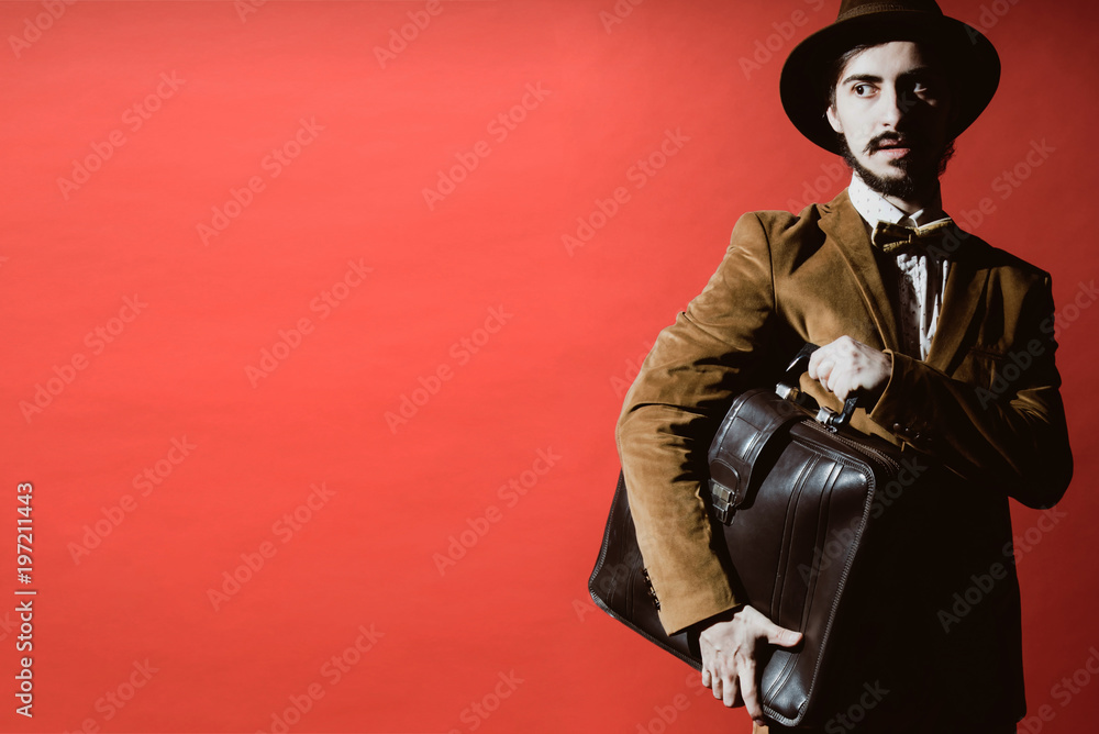 Naklejka premium man posing in studio with suitcase in hands