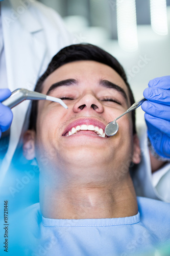 Fototapeta Naklejka Na Ścianę i Meble -  Young attractive man receiving a dental treatment. Close up shot.