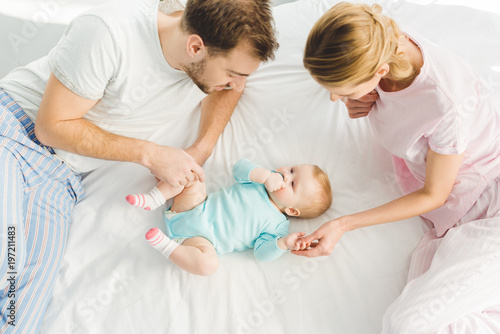 High angle view of young parents with infant daughter in bed