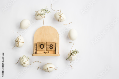 Easter white eggs are minimalistically decorated with twine and gypsophila. With a wooden calendar. 08 April 2018. Easter. Top view, flat lay photo