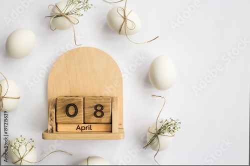 Easter white eggs are minimalistically decorated with twine and gypsophila. With a wooden calendar. 08 April 2018. Easter. Top view, flat lay photo