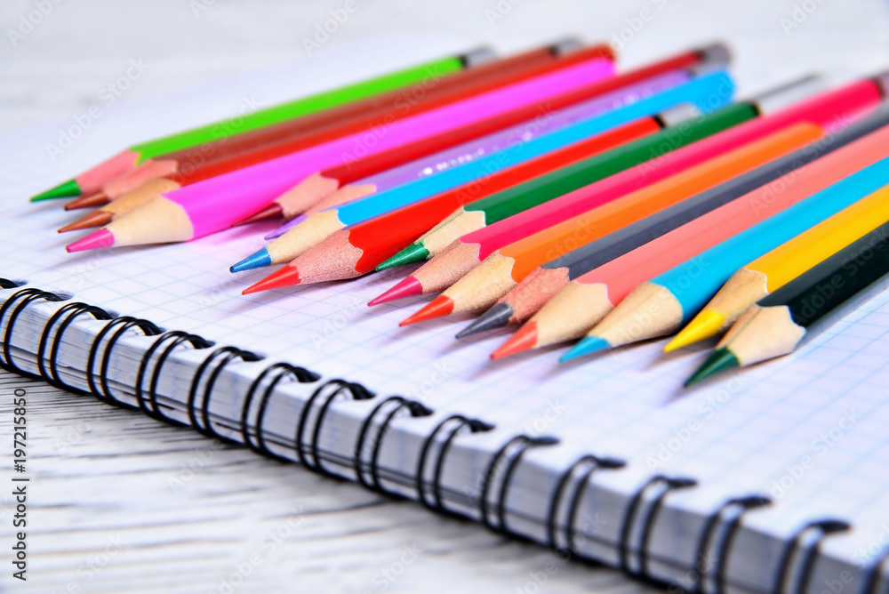 Color pencils lying on a pad with a spiral. Gray natural background, blur Color pencils lying on a pad with a spiral. Gray natural background, blur