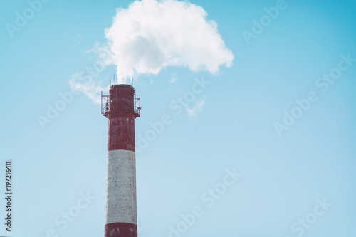 The smoke from a factory chimney on background of blue sky