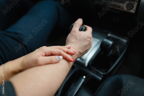 A young couple in love holding hands, holding on the shift lever going into the road trip. A man and a girl go together by car.