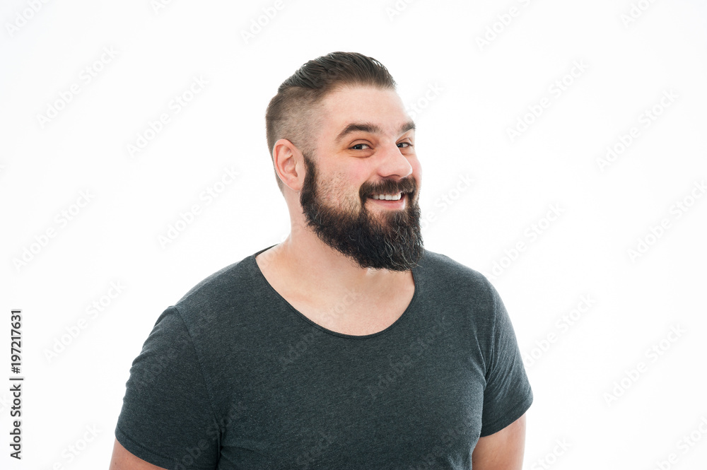 Studio shot of joyfully smiling bearded european male model in blue t-shirt, looking at camera with broad smile. Positive emotions, feelings and reaction Studio shot of joyfully smiling bearded european male model in blue t-shirt, looking at camera with broad smile. Positive emotions, feelings and reaction