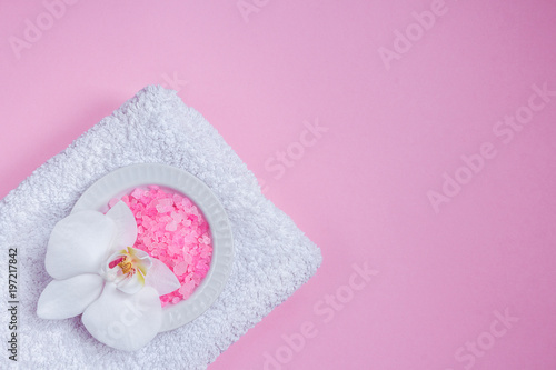 Spa background, flat lay layout with pink sea salt, candles and aroma oils and cosmetic care products on a pink background