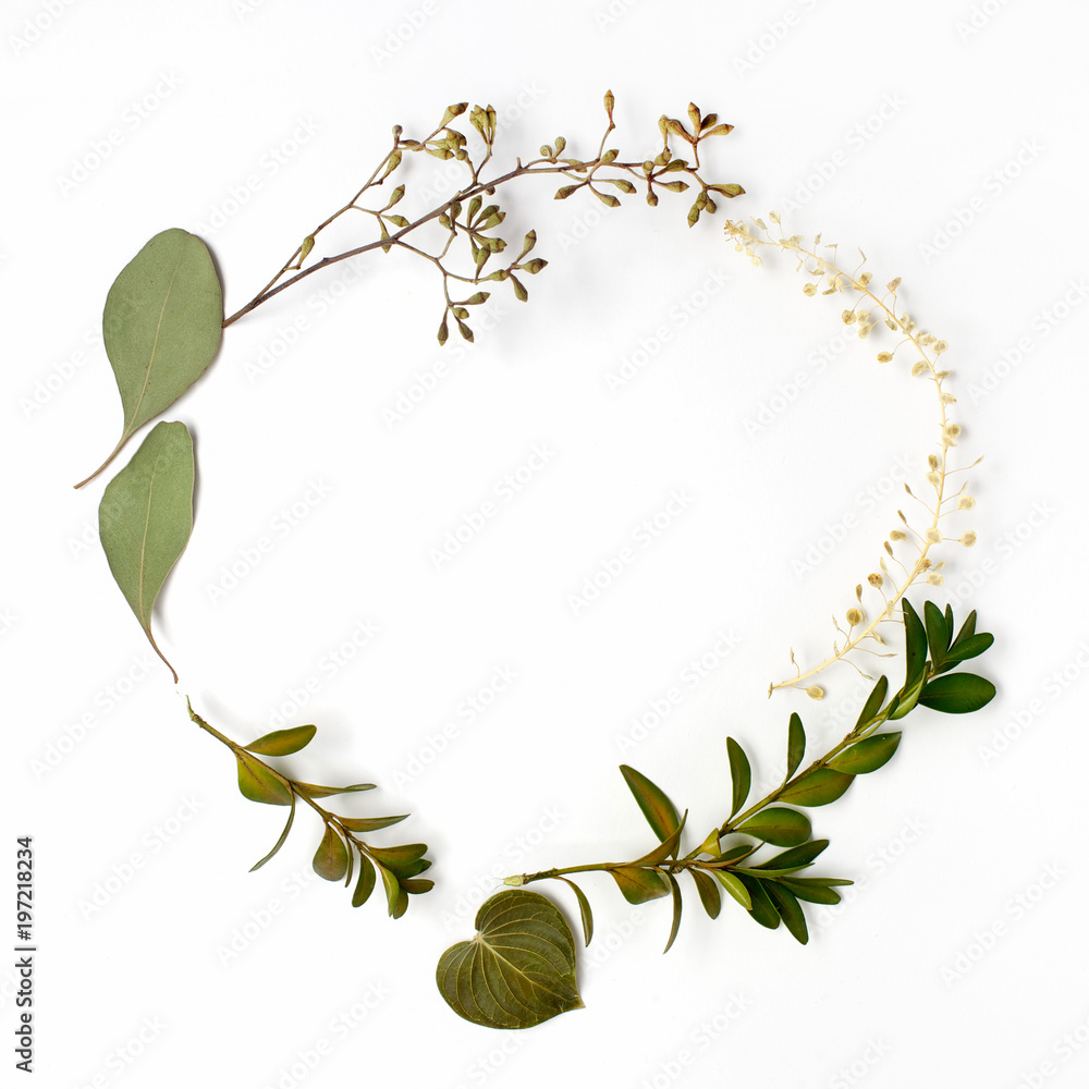 Fototapeta premium Round circle frame made of green branches and leaves on white background. Flat lay, top view