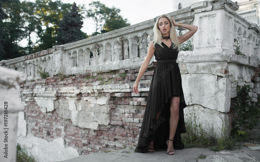 Portrait of beautiful young blonde girl in black dress. Fashion photo