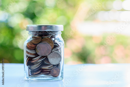 Coins in glass jar against ...