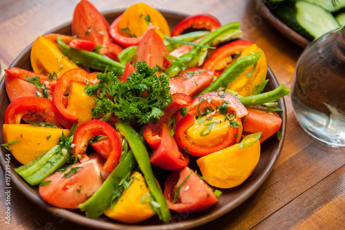 Multi-colored fresh cutted vegetables on a wooden plate